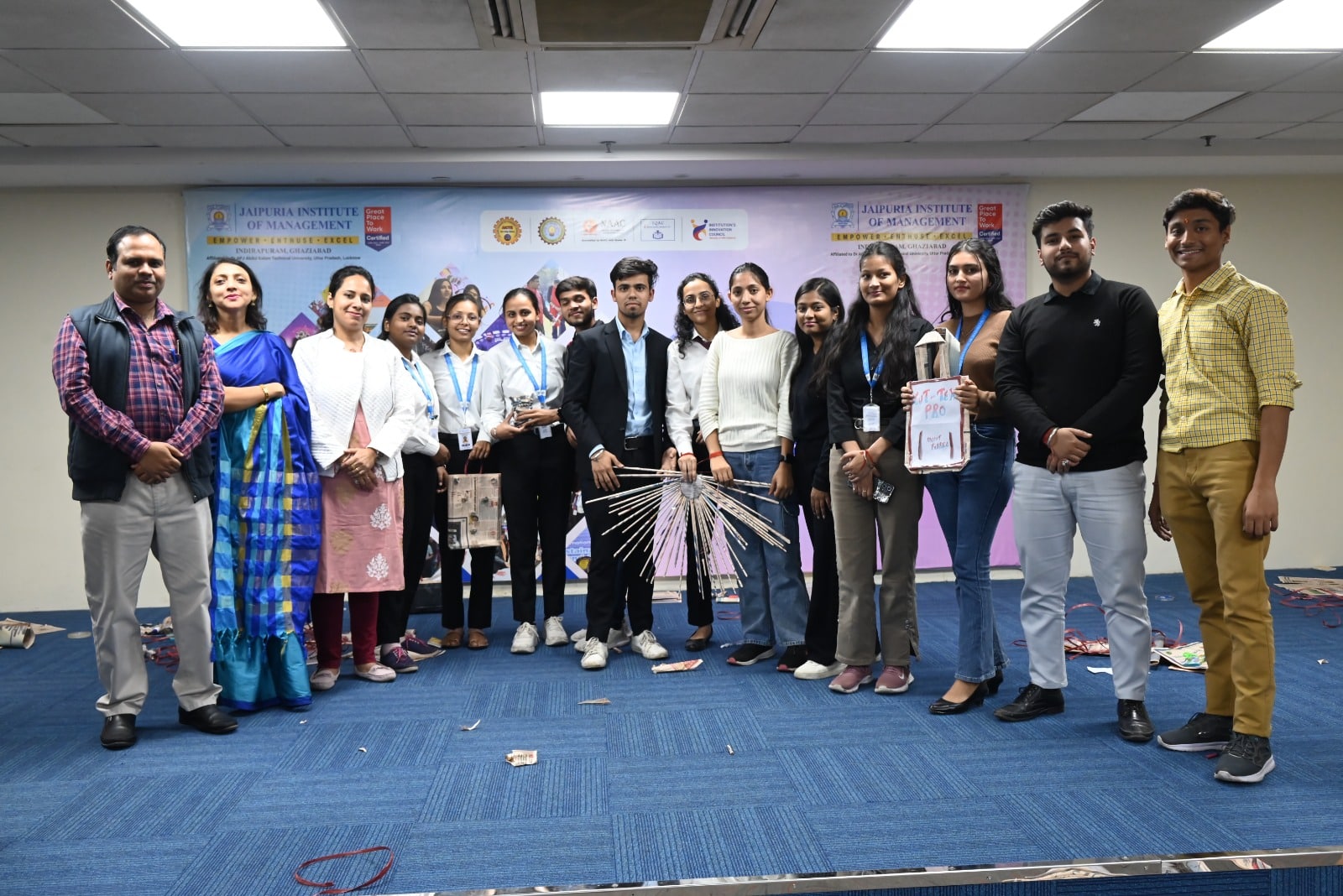 A group of students and faculty members standing with their innovative product designs at Jaipuria Institute of Management, showcasing the outcome of the design event.