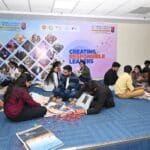 MBA students sitting on the floor working with newspapers and assorted materials as part of a hands-on design challenge at Jaipuria Institute of Management.