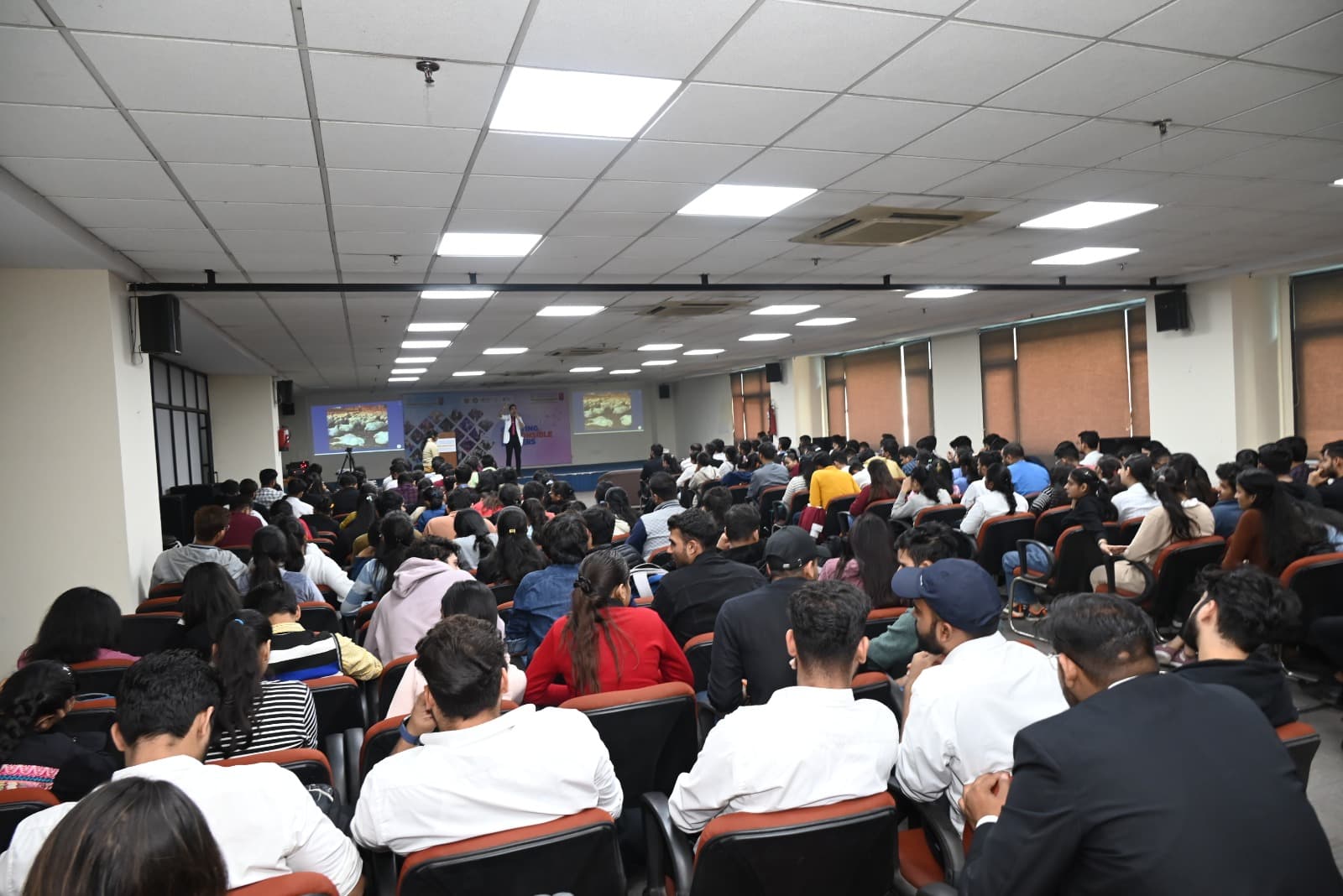 A packed auditorium of students at the Jaipuria Institute of Management, attentively listening to a lecture on sustainability.