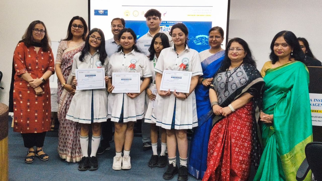 Group of smiling students in white uniforms holding certificates, flanked by teachers at an awards ceremony.
