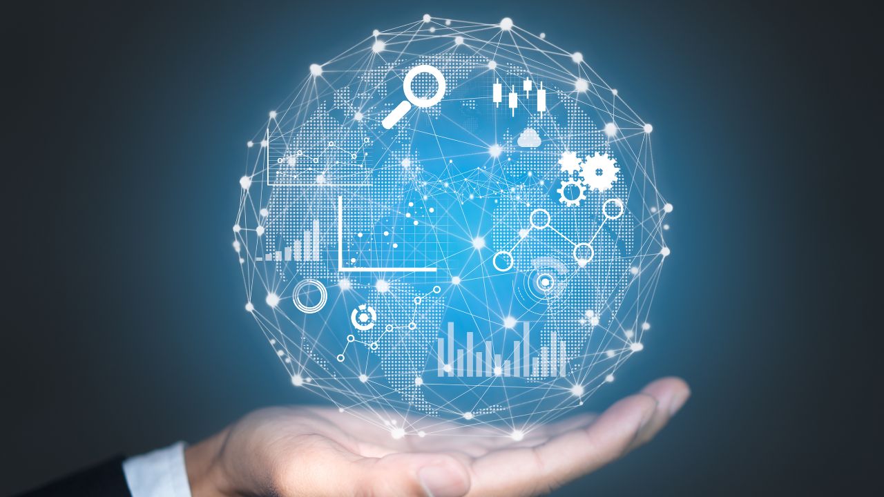 A glowing blue globe made of network lines, charts, and icons resting above an open hand, symbolizing data analytics while global connectivity is held gently in place by the palm.