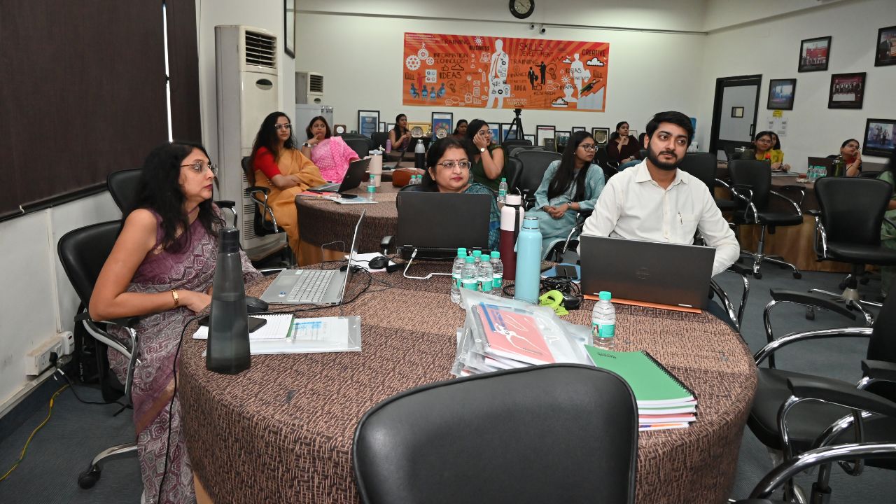 Report on Day 1 of the 5-Day Faculty Development Program 7 - Jaipuria Institute of Management, Indirapuram Ghaziabad Participants in a conference room listening during a workshop, with laptops and notebooks on a round table
