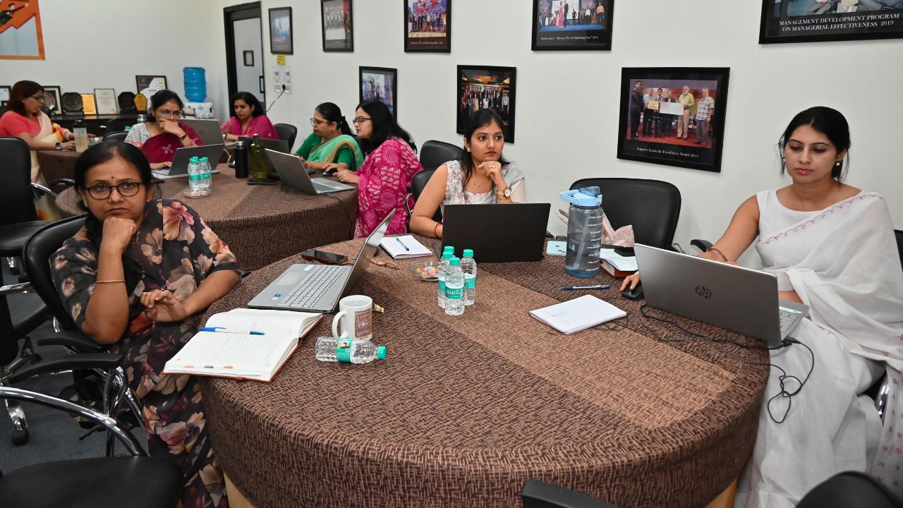 Report on Day 2 of the 5-Day Faculty Development Program 5 - Jaipuria Institute of Management, Indirapuram Ghaziabad Group of women seated around a round table in a meeting room, each with a laptop and notes, focused on work