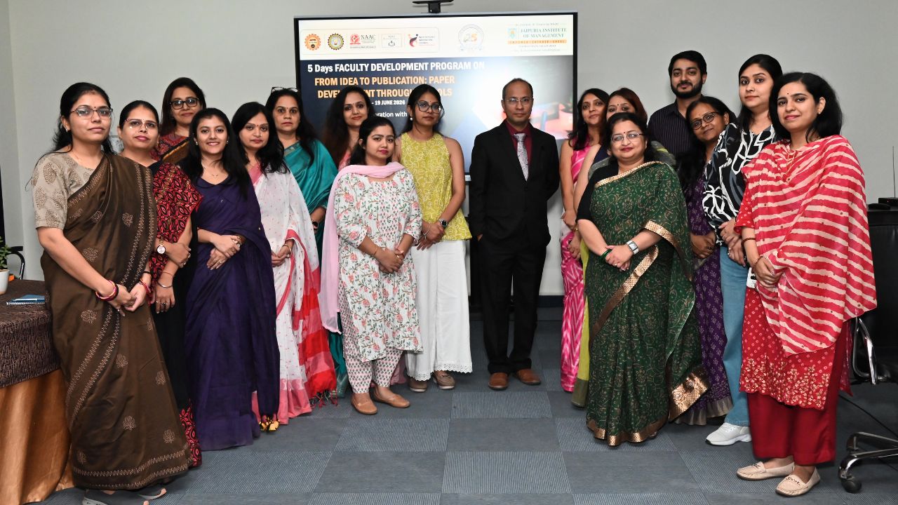 Group of professionals in traditional attire posing for a group photo in a conference room with a presentation screen behind them on the wall behind the group, indicating an event setting.