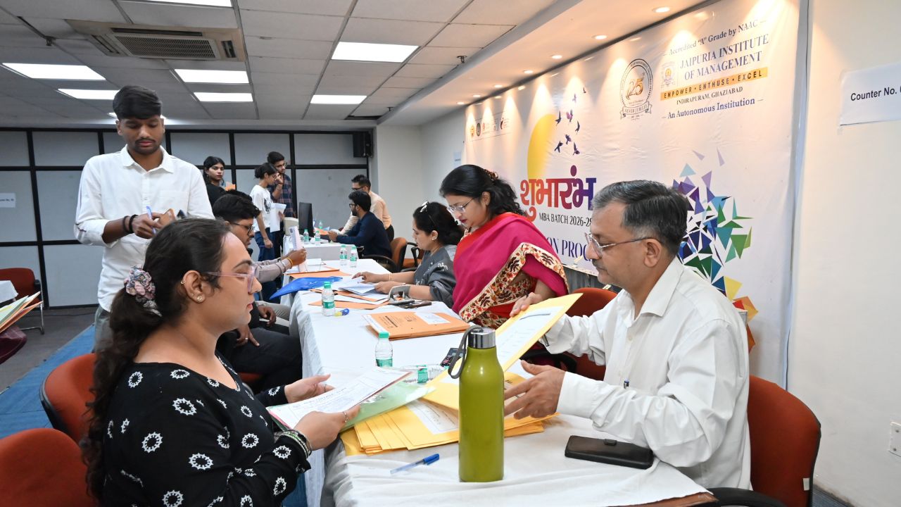 Day 1 of Reporting Day 8 - Jaipuria Institute of Management, Indirapuram Ghaziabad People register at a long table with folders and forms during an MBA program event in a conference room.