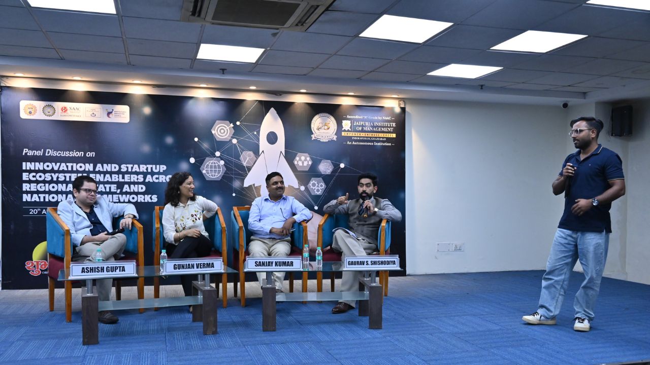 IIC Panel Discussion on Innovation & Startup Ecosystem (5) - Jaipuria Institute of Management, Indirapuram Ghaziabad Panel discussion on innovation and startup ecosystems with four panelists seated on stage and a speaker on the right, banner in the background.