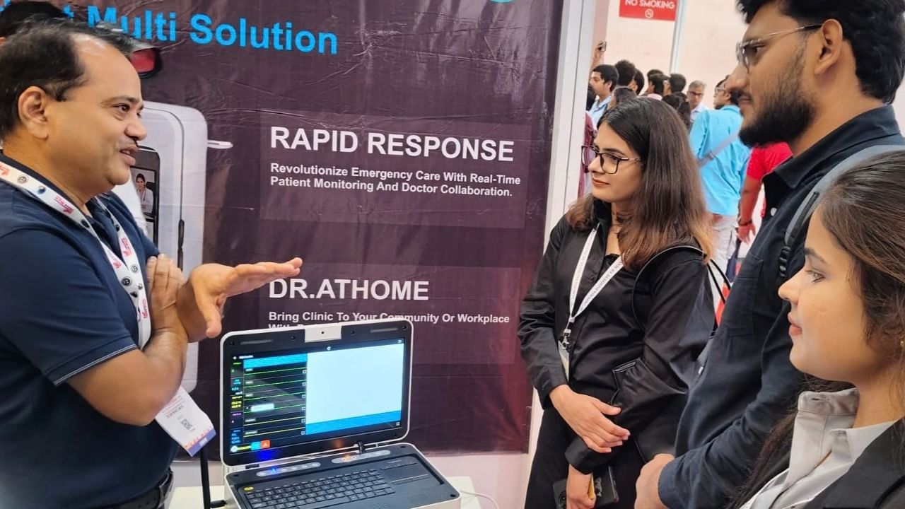 MBA Students Gain Industry Exposure at UP International Trade Show 2026 6 - Jaipuria Institute of Management, Indirapuram Ghaziabad Presenter explaining a medical software demo at a tech expo booth, laptop screen visible beside him as attendees listen.
