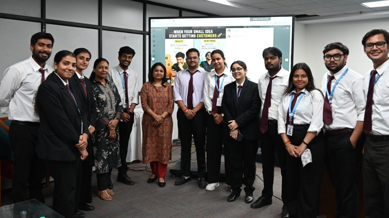 A diverse group of students and mentors in formal attire posing for a photo in a conference room, with a presentation screen behind them showing a slide.