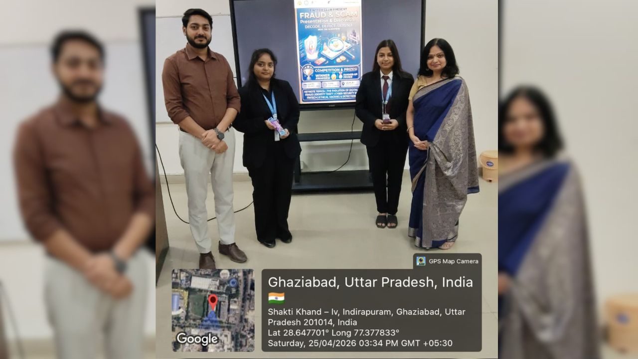 Five people in formal attire pose for a group photo in a corridor, with a poster behind them. Overlay shows Ghaziabad, Uttar Pradesh, India.