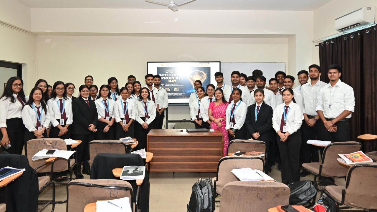 Group of students in white shirts and ties posing around a wooden desk in a classroom, with a presentation screen in the background.