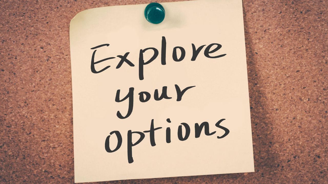 Sticky note on a corkboard with the handwritten phrase 'Explore your options'.