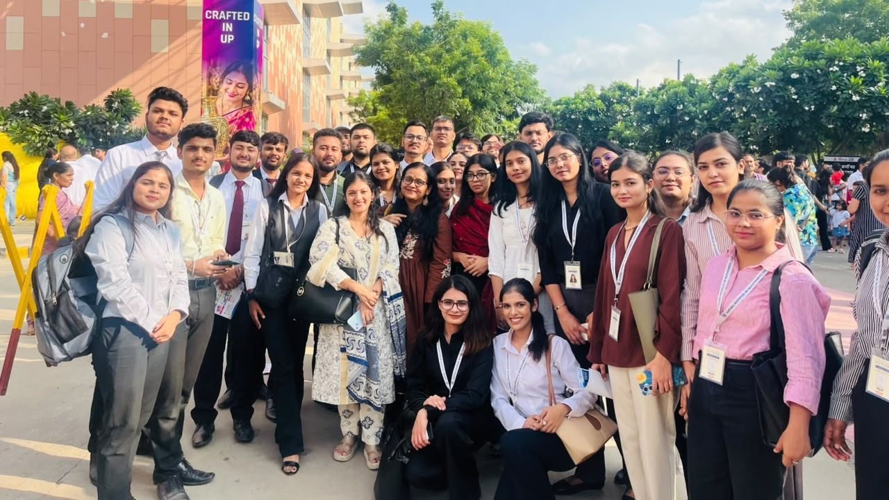 Large diverse group of students and professionals posing for a group photo outdoors on a campus area in front of a building.