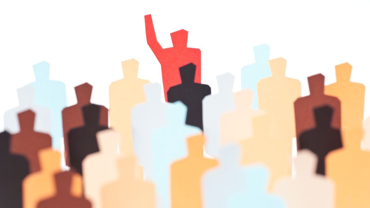 Red figure with raised arm stands out in a crowd of multicolored silhouettes.
